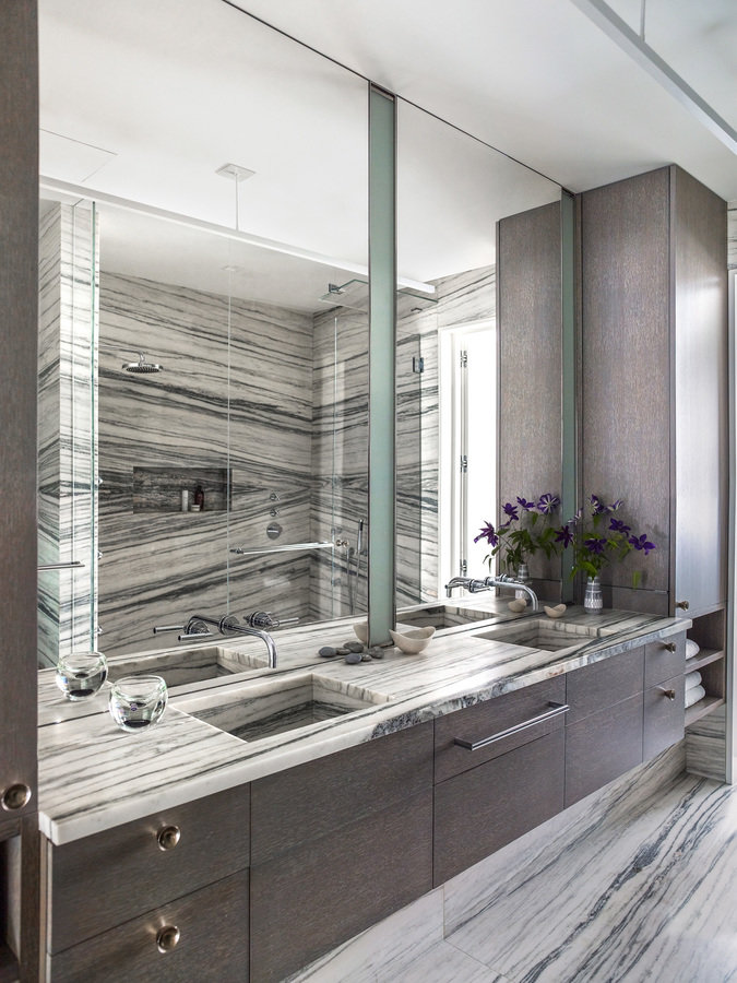 Bathroom with double vanity and mirrors, cerused oak cabinetry and green and white striated stone counter, floor and shower.