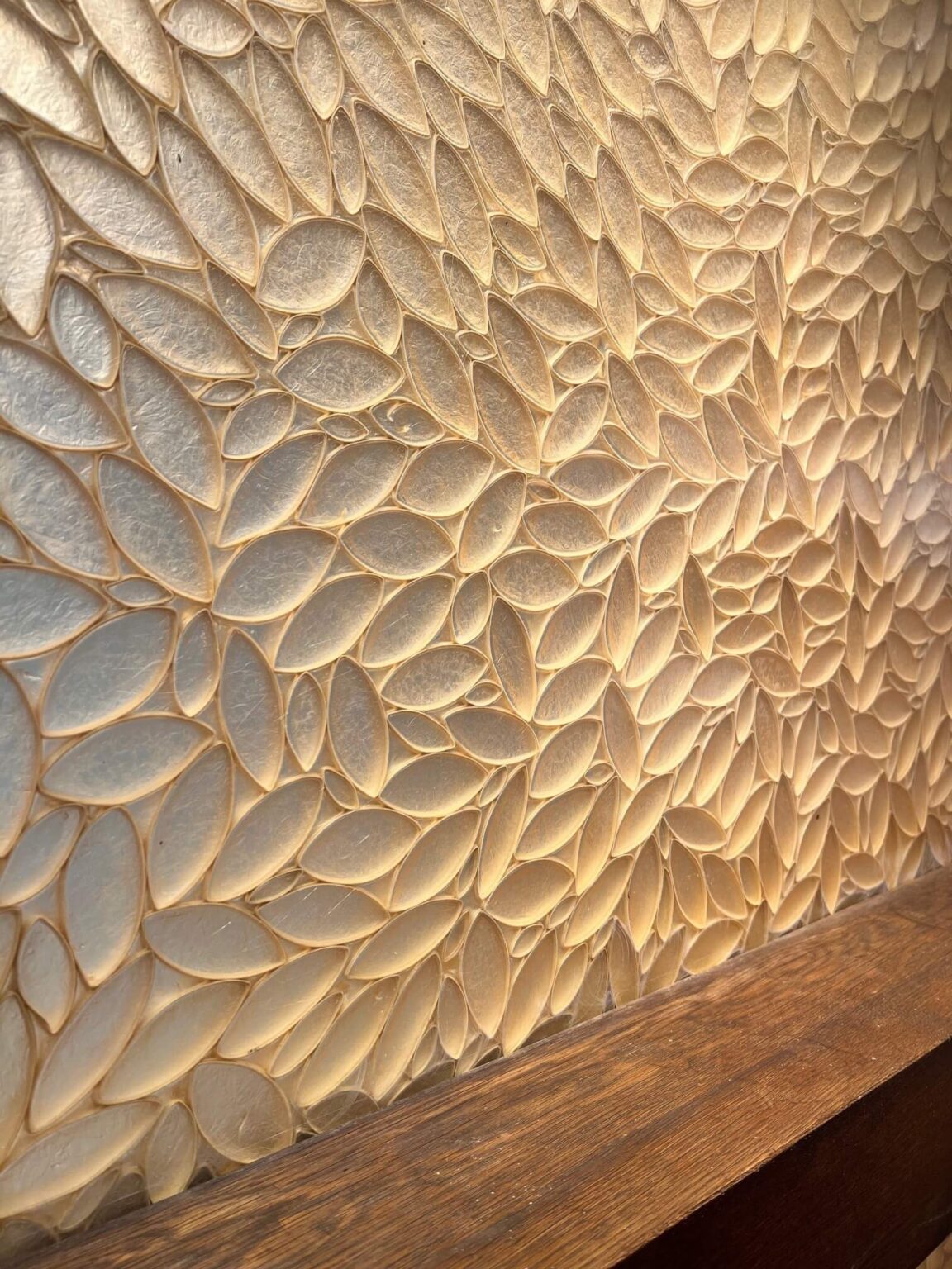 Close-up of a decorative wall panel of white rice paper and leaf shapes with a wood trim.