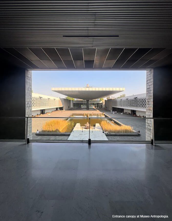 A picture window inside a marble-floored building showing a view of a walled courtyard and a modern canopy structure.