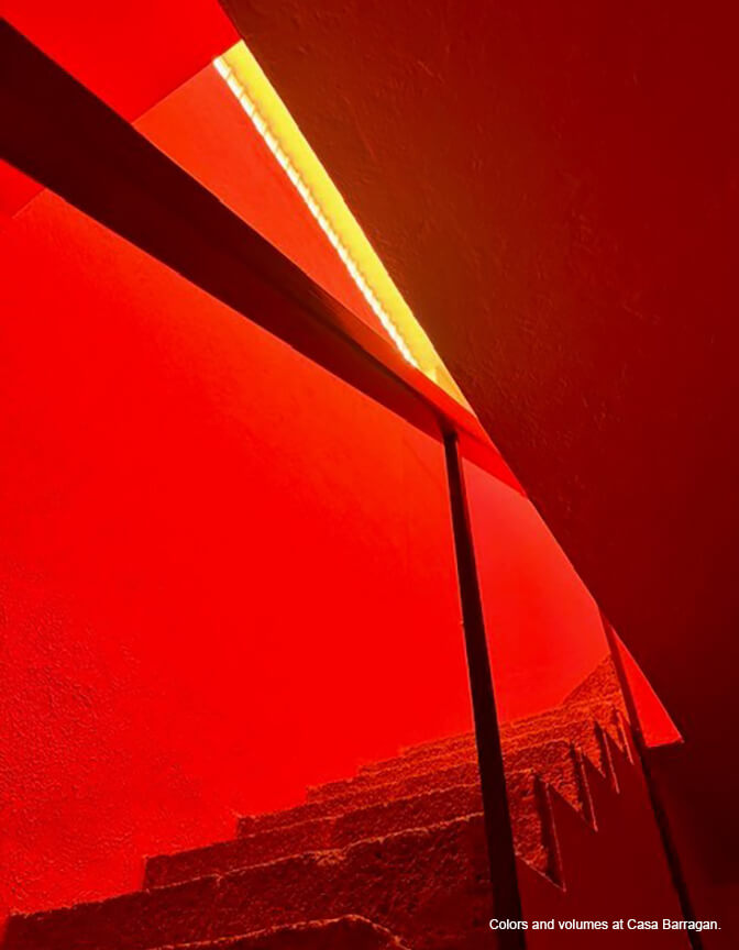 An abstract view of a bright red space with a concrete staircase, an angled wall and a strip of yellow showing.
