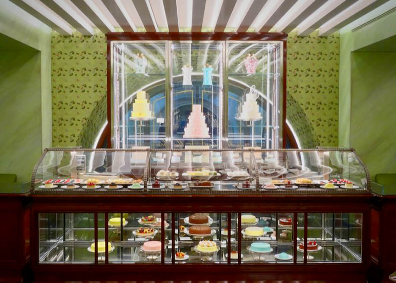 Spring green walls and dark wood and glass cases displaying colorful cakes and desserts at Marchesi 1824 in Milan.