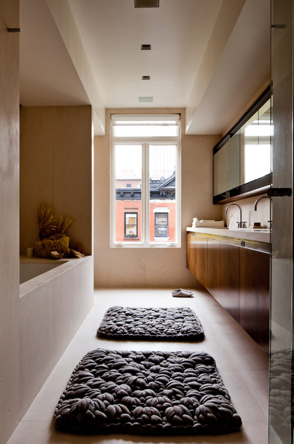 Bathroom with wall-mounted double vanity cabinet and mirror, built-in tub, window with city view and oversize knotted rugs.