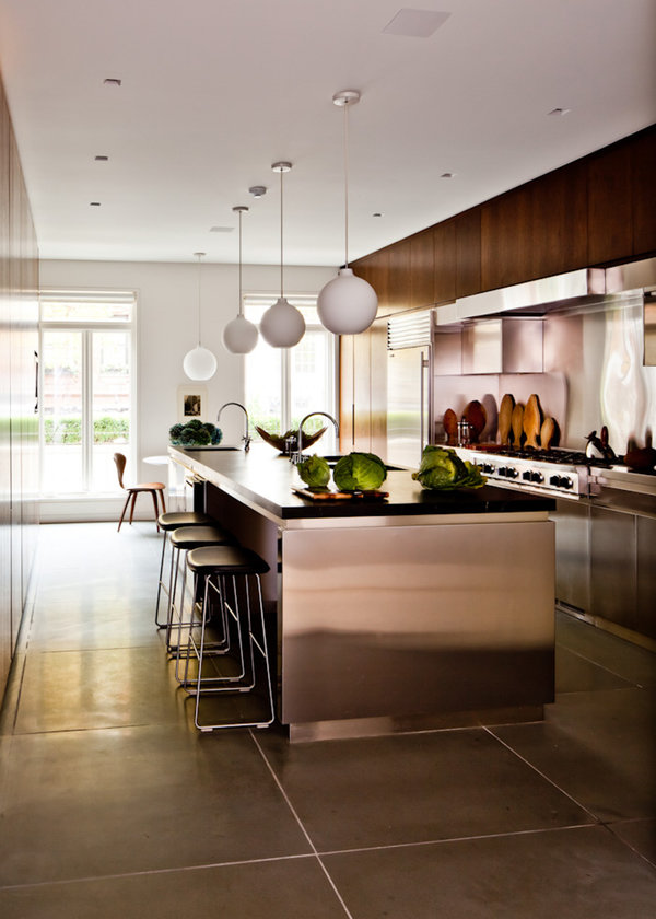 Chef’s kitchen with walnut millwork, stainless steel appliances, counter and stools and hanging globe chandeliers.