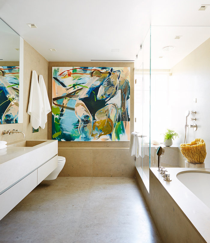 Primary bathroom in neutral palette with artwork on rear wall, wall-mounted sink vanity on left, shower and tub on right.