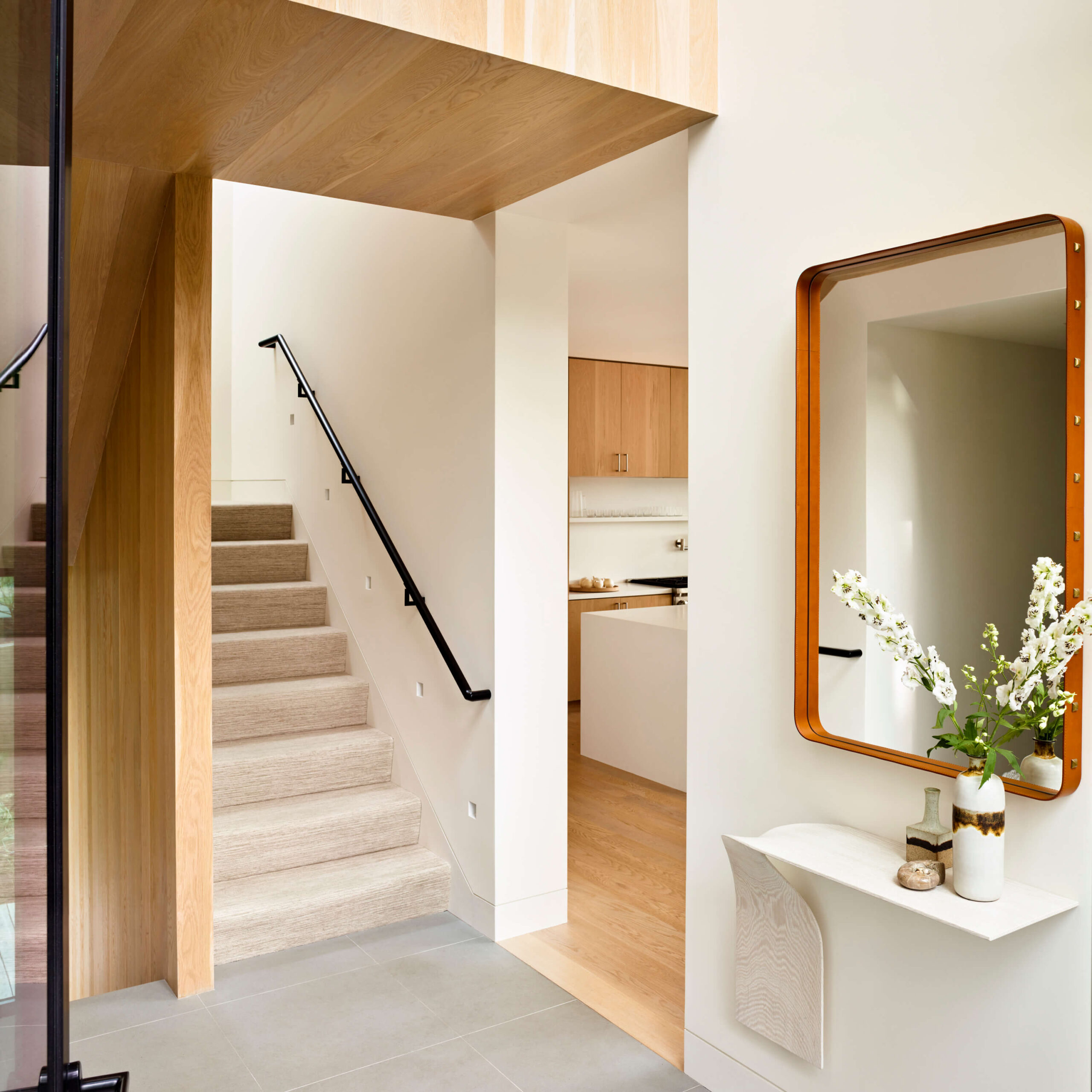 Entry with sculptural console table and mirror and view to stairway and kitchen.