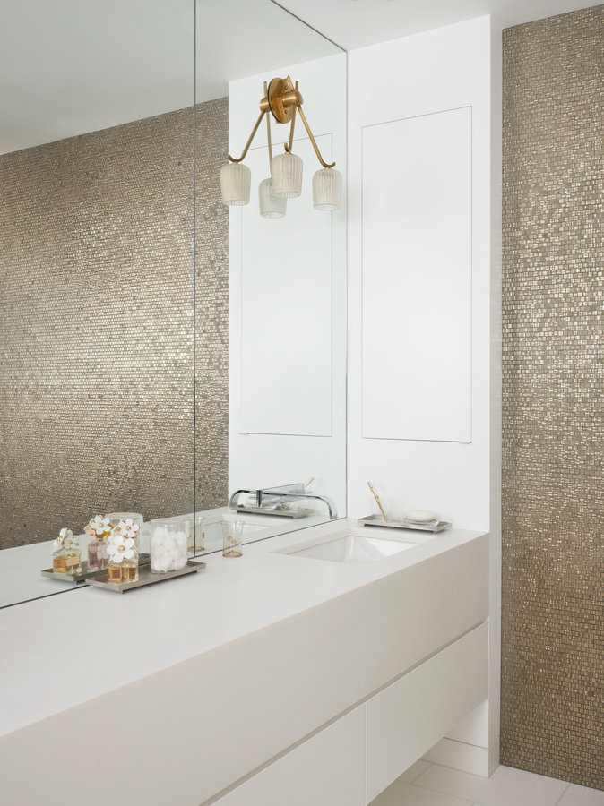 Mirrored wall of primary bathroom with floating white lacquer vanity, antique two-shade sconce and platinum mosaic tile wall.