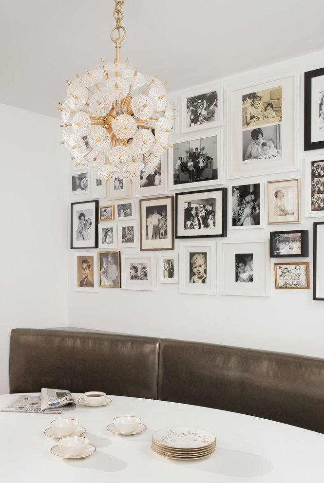 Breakfast table with china teacups, taupe leather banquette, dandelion chandelier and photo gallery wall in background.