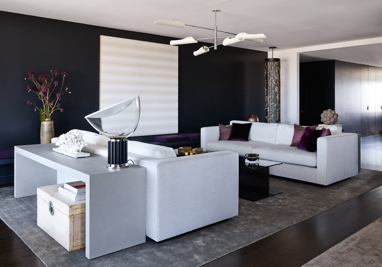 Modern living rooms with black walls, white sofas, white artwork, gray area rug and white multilight ceiling fixture.