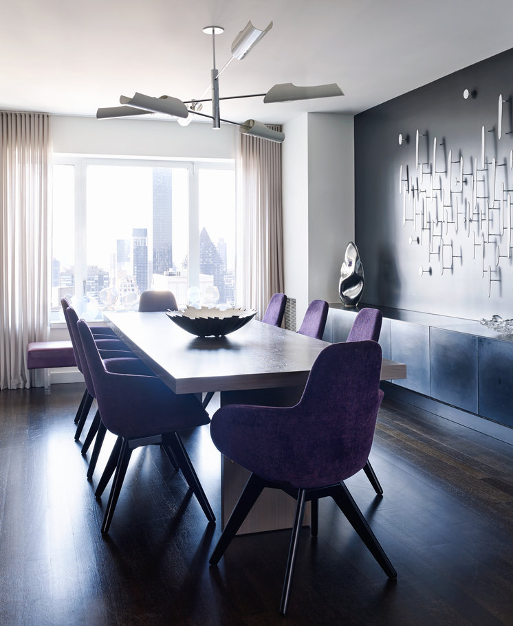 Black and white dining room, dark wood floor, modern table with purple chairs; window with white curtains in background.